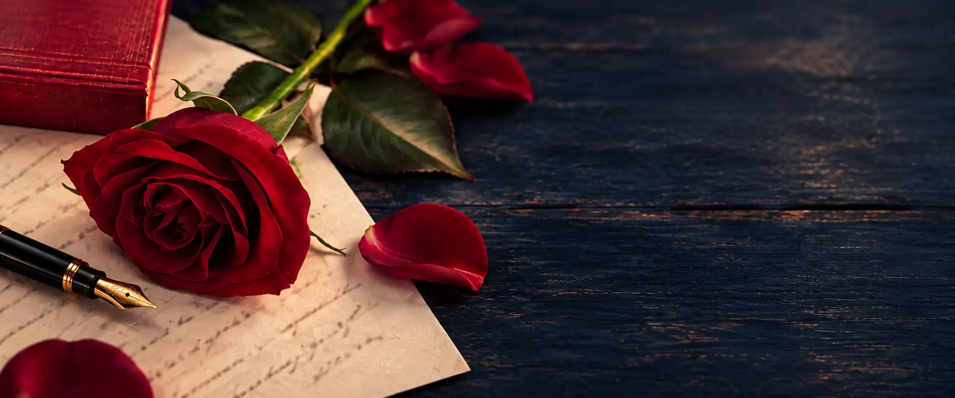 Rose rouge et stylo-plume posés sur une déclaration d’amour